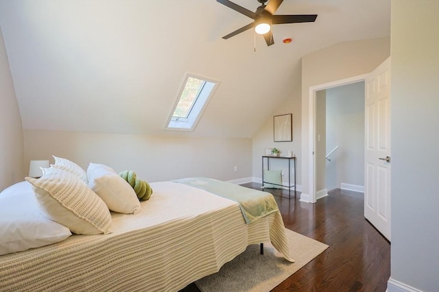bedroom featuring wood finished floors, lofted ceiling, a skylight, baseboards, and a ceiling fan