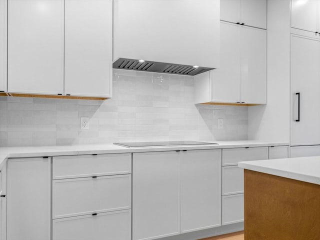 kitchen featuring black electric stovetop, white cabinetry, light countertops, custom exhaust hood, and tasteful backsplash