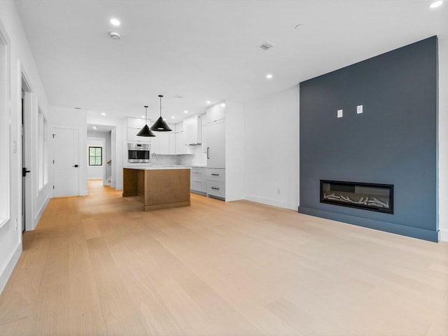 unfurnished living room with light wood-style flooring, recessed lighting, baseboards, and a large fireplace