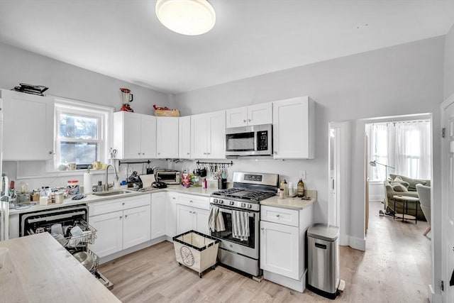 kitchen featuring white cabinetry, sink, stainless steel appliances, and light hardwood / wood-style floors