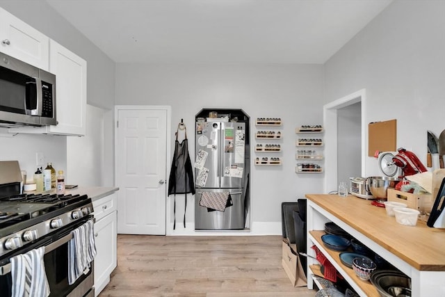 kitchen featuring stainless steel appliances, white cabinets, and light wood-type flooring