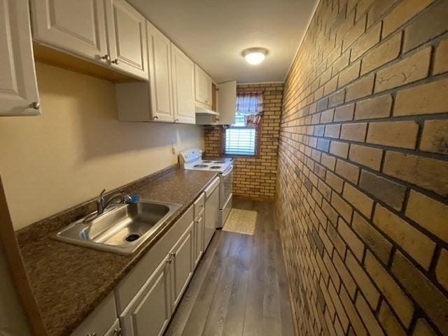 1025 Main St, Worcester, MA 01603 - kitchen featuring white electric stove, under cabinet range hood, brick wall, white cabinets, and dark countertops