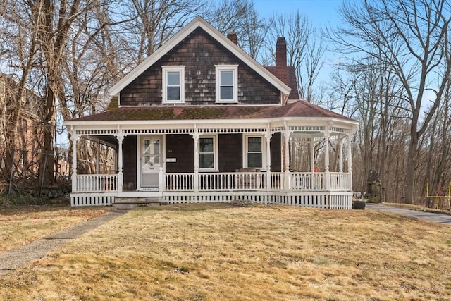 view of front of home with a front yard, a porch, and a chimney