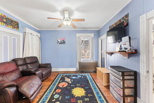 living area with crown molding, radiator heating unit, ceiling fan, and wood finished floors