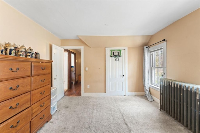 bedroom with light colored carpet, radiator heating unit, baseboards, and lofted ceiling