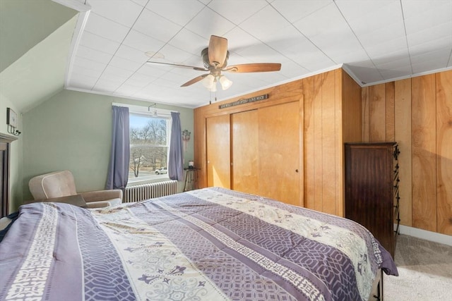 carpeted bedroom featuring a closet, wood walls, ceiling fan, and vaulted ceiling