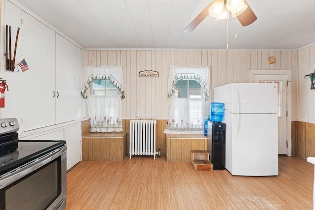 kitchen featuring stainless steel electric range oven, radiator, light wood-style floors, and freestanding refrigerator