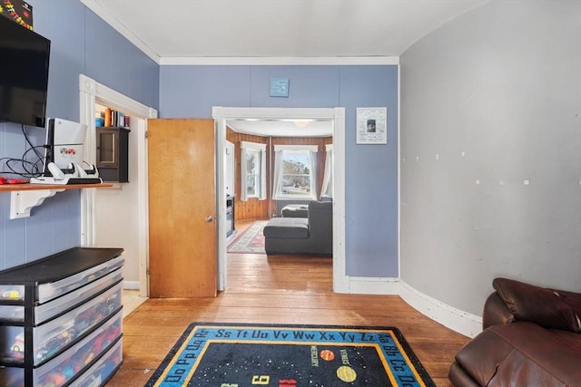 interior space with baseboards, wood-type flooring, and ornamental molding