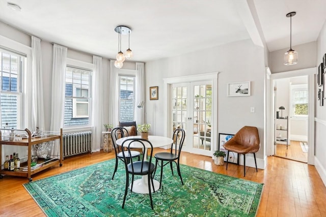 dining room with light wood-type flooring, french doors, and radiator heating unit