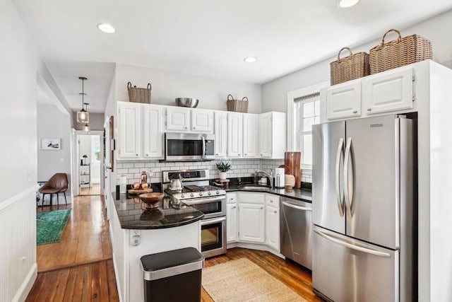 kitchen featuring a sink, stainless steel appliances, decorative backsplash, and dark countertops