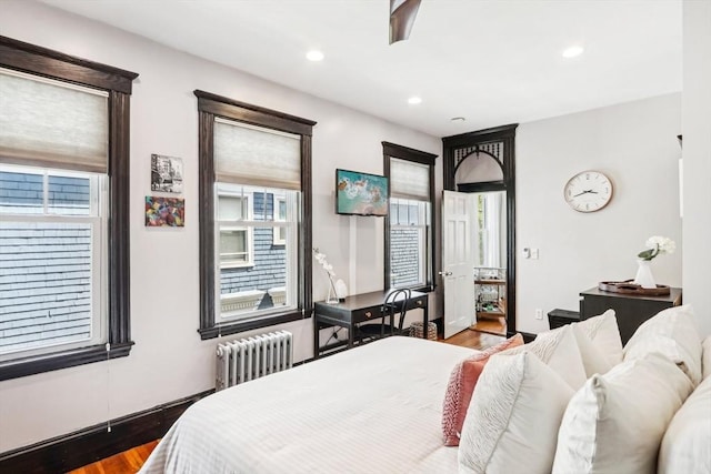 bedroom with recessed lighting, wood finished floors, and radiator heating unit