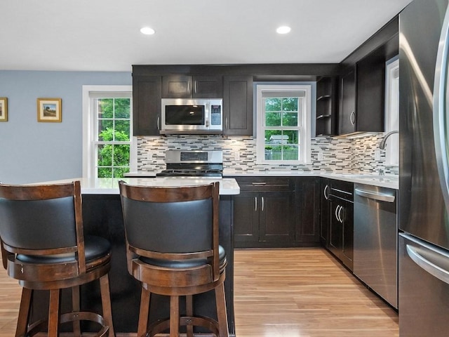 4 University Park, Waltham, MA 02453 - kitchen featuring appliances with stainless steel finishes, light countertops, light wood-style floors, backsplash, and healthy amount of natural light