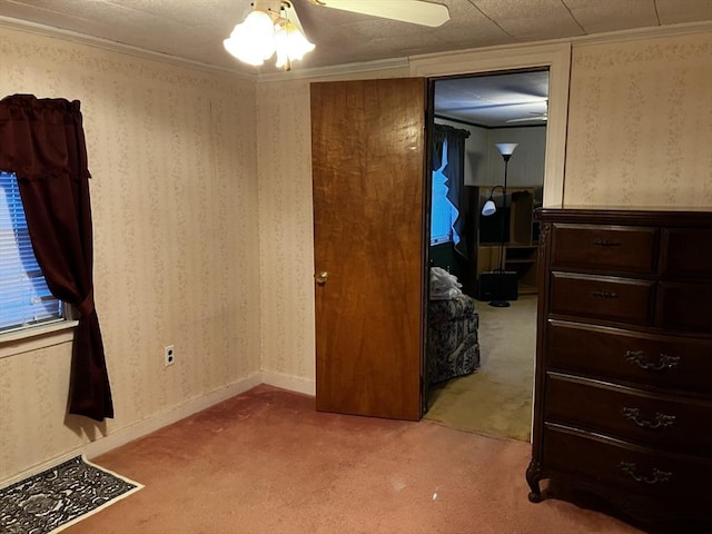 bedroom featuring light colored carpet, crown molding, baseboards, and wallpapered walls