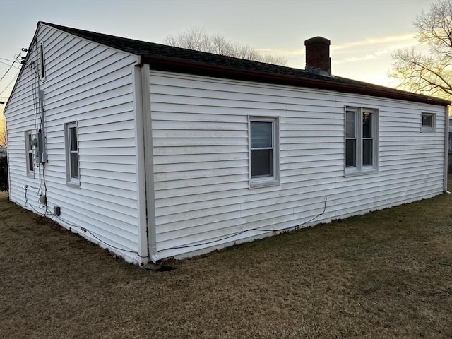 view of side of property featuring a lawn and a chimney