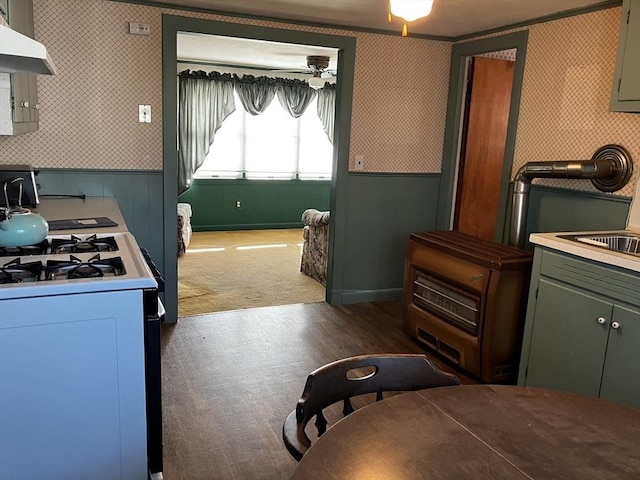 kitchen featuring wallpapered walls, white range with gas cooktop, electric panel, ceiling fan, and wall chimney range hood