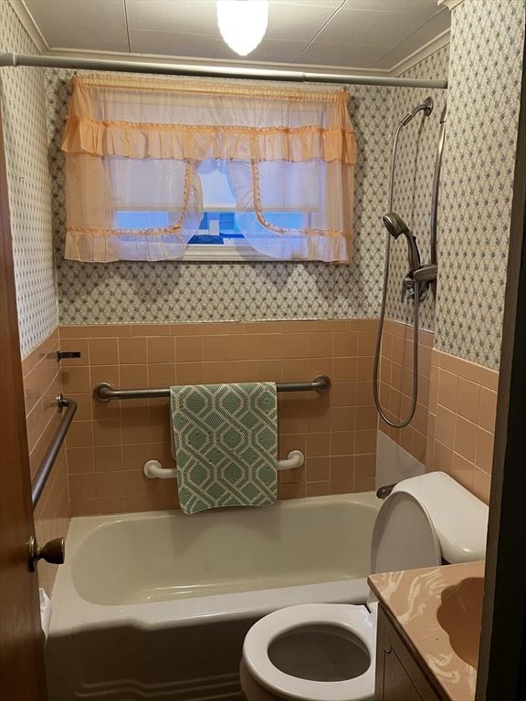 full bath with toilet, tile walls, vanity, wainscoting, and a shower with curtain