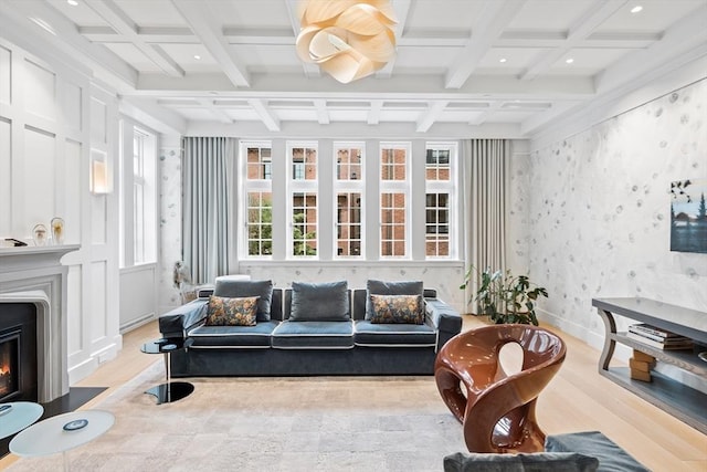 living area with wallpapered walls, baseboards, beamed ceiling, a glass covered fireplace, and coffered ceiling