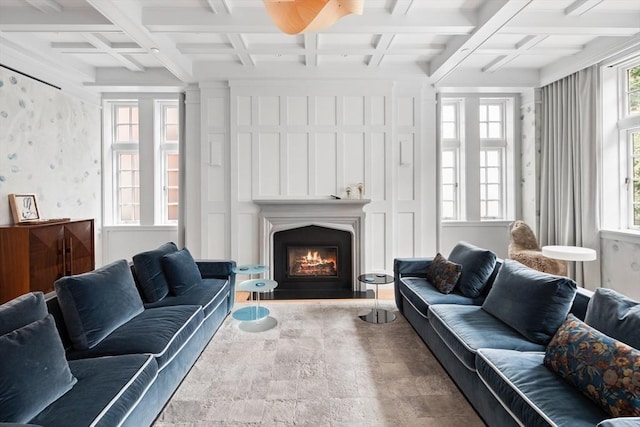 living room with wallpapered walls, a healthy amount of sunlight, coffered ceiling, and a lit fireplace