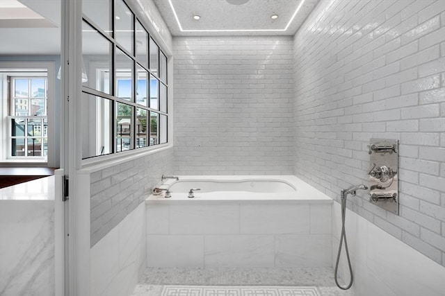 bathroom with tile walls, plenty of natural light, and a bath