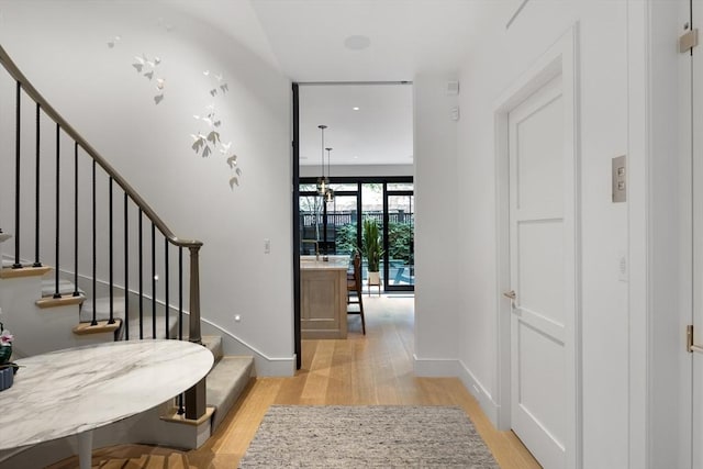 hallway featuring stairway, baseboards, and light wood finished floors