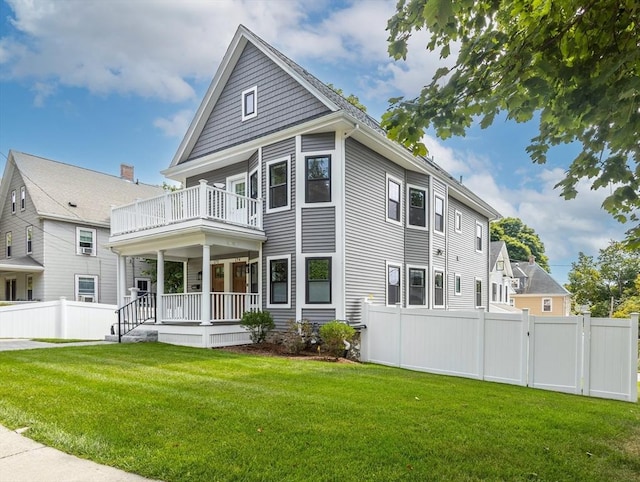 view of front of home featuring a balcony, a front lawn, and covered porch