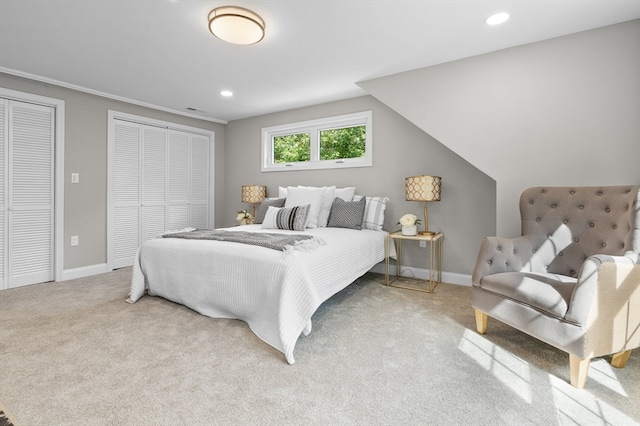 carpeted bedroom with multiple closets and lofted ceiling