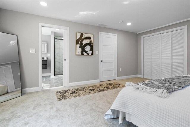 carpeted bedroom with ornamental molding, a closet, and ensuite bathroom