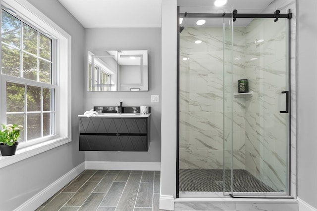 bathroom with a wealth of natural light, a shower with door, and vanity