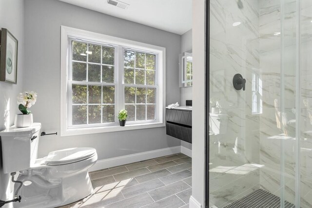 bathroom featuring vanity, a shower with shower door, and toilet