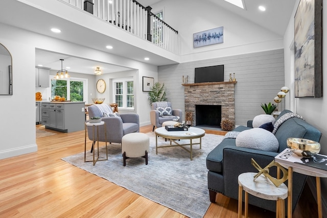 living room featuring a fireplace, light hardwood / wood-style flooring, and high vaulted ceiling