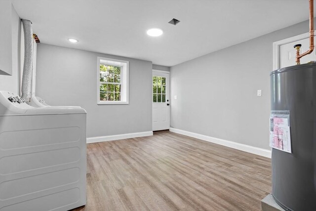 interior space with light hardwood / wood-style floors, electric water heater, and separate washer and dryer