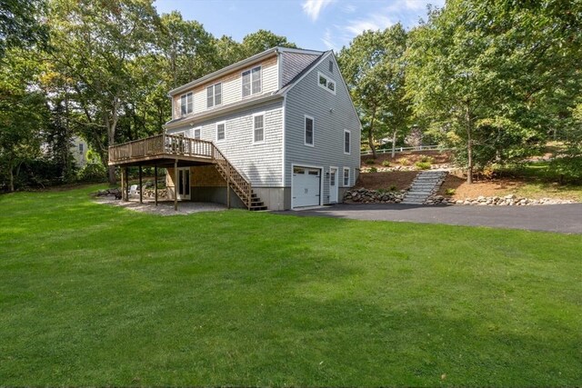 back of house featuring a lawn, a deck, and a garage