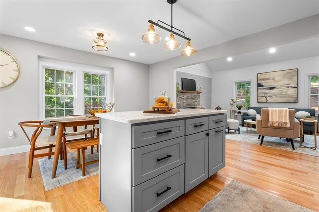 kitchen with hanging light fixtures, light hardwood / wood-style floors, a kitchen island, and plenty of natural light