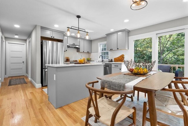 kitchen featuring gray cabinetry, stainless steel refrigerator, pendant lighting, light wood-type flooring, and a center island