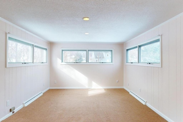 spare room with a baseboard heating unit, plenty of natural light, and carpet