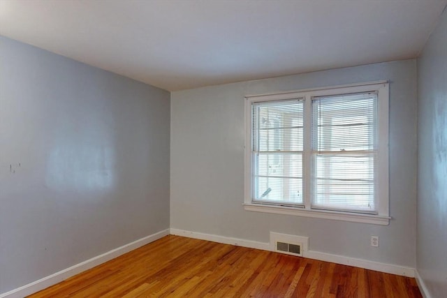 unfurnished room with light wood-style flooring, visible vents, and baseboards