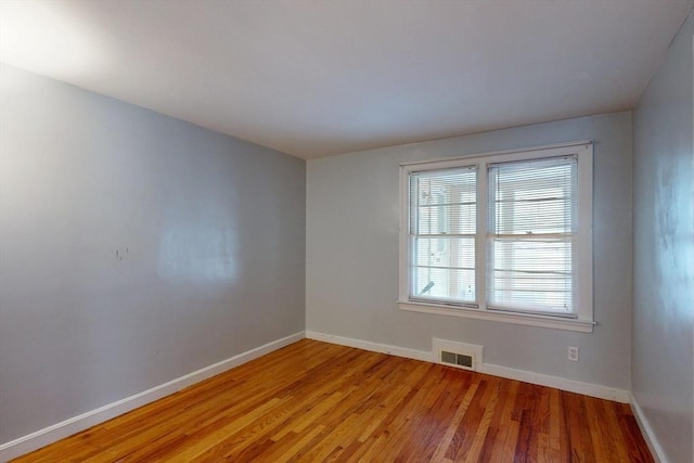 unfurnished room featuring light wood-style flooring, visible vents, and baseboards