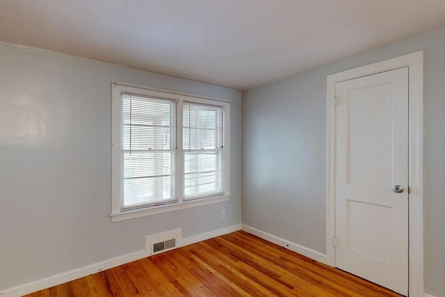 empty room featuring light wood-type flooring, visible vents, and baseboards