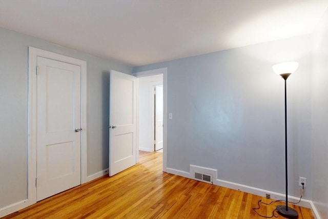 unfurnished bedroom with visible vents, light wood-style flooring, and baseboards