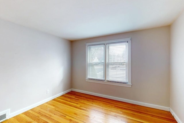 empty room featuring light wood-type flooring, visible vents, and baseboards