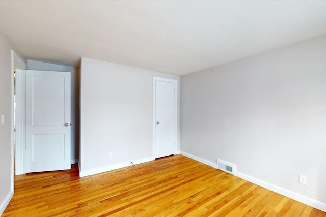 spare room with light wood finished floors, visible vents, and baseboards