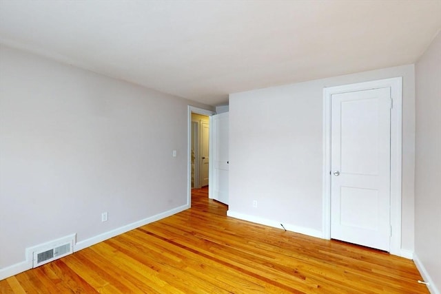 spare room featuring light wood-style floors, baseboards, and visible vents