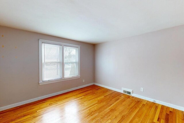 spare room featuring light wood-style floors, baseboards, and visible vents