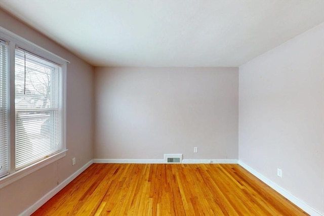 empty room with light wood-type flooring, baseboards, and visible vents