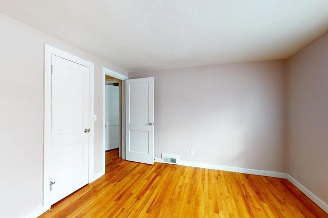 unfurnished bedroom with light wood finished floors, visible vents, and baseboards