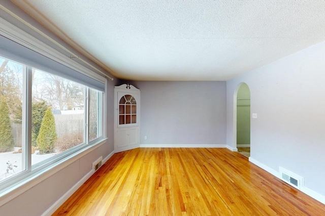 spare room with baseboards, visible vents, and arched walkways