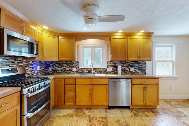 kitchen with a healthy amount of sunlight, appliances with stainless steel finishes, decorative backsplash, and a sink