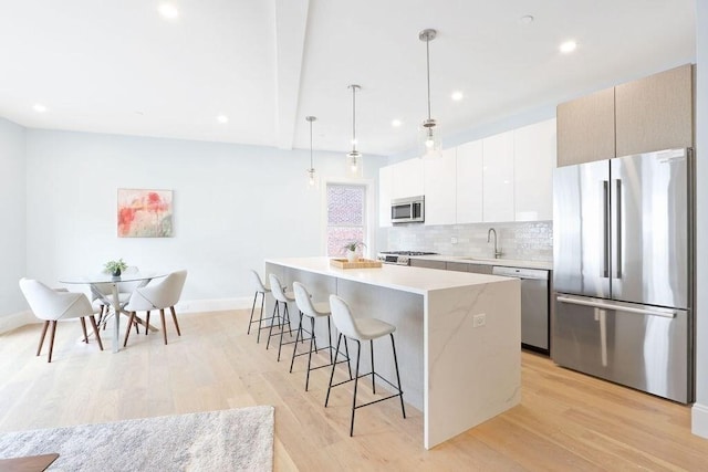 kitchen featuring a breakfast bar, stainless steel appliances, backsplash, a kitchen island, and recessed lighting
