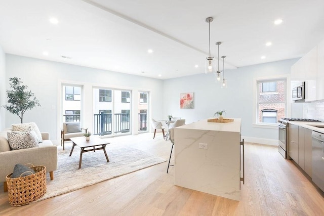 kitchen featuring a center island, a breakfast bar, stainless steel range with gas stovetop, modern cabinets, and light wood-style floors