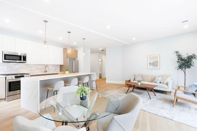 dining space with baseboards, light wood finished floors, and recessed lighting